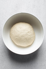 Fototapeta na wymiar Bread dough resting in a bowl, dough that is rising, proofing dough in a white bowl
