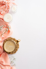 Hello spring concept. Top view vertical photo of cup of frothy coffee on wicker serving mat pink plaid candles and gypsophila flowers on isolated white background with copyspace