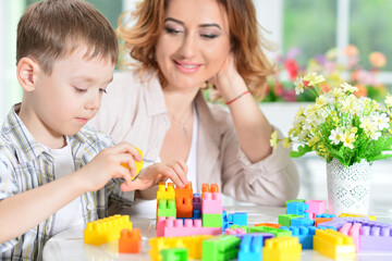 Woman and little boy playing with colorful plastic blocks 