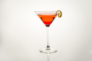 Martini glass with pink lady cocktail, lemon twist  isolated on a white background