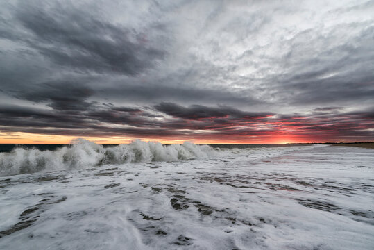 Scenic view of waves against cloudy sky during sunset