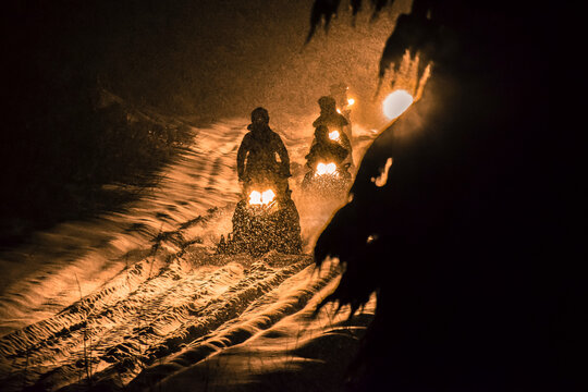 People driving snowmobiles at night, Callaghan Valley, Whistler, British Columbia, Canada