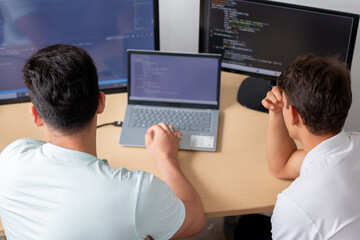 Fototapeta premium Two young programmers in an office, preoccupied as they work on a programming and technology project