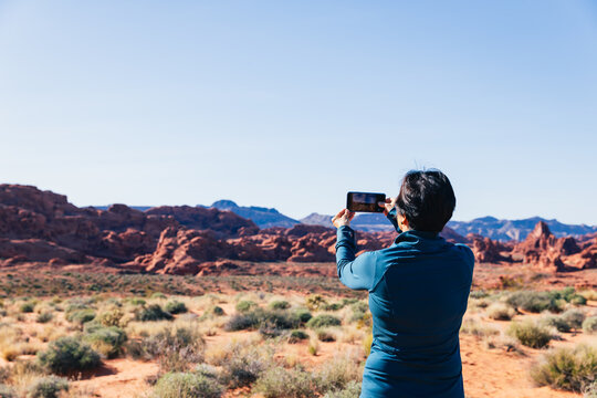 Senior Asian woman taking a photo of a desert landscape with her camer
