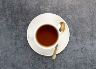 Cup of black hot tea with a spoon on a green background. Top view.