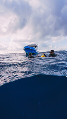 split shot of two divers on the surface next to a boat