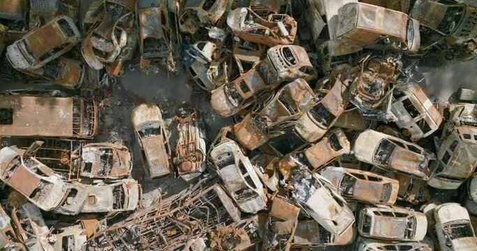 UKRAINE - CIRCA 2022 - aerial of wrecked and burned cars in the car cemetery sitting in a pile many with bullet holes from Russian aggression, Irpin.