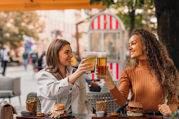 Two girls are sitting in the cafe, having fun and making a toast.