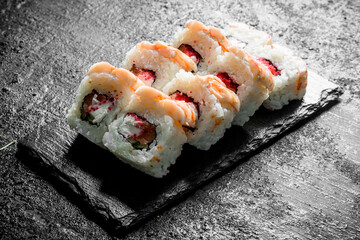 Traditional sushi rolls with shrimp on a stone Board.