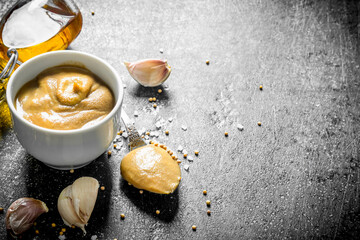 Mustard in a bowl with garlic cloves.