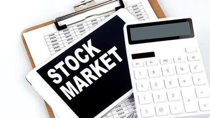 STOCK MARKET text on a tablet with chart, calculator and pen