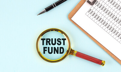 TRUST FUND text on magnifier with clipboard on blue background