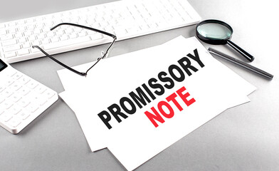 PROMISSORY NOTE text on a paper with keyboard, calculator on grey background