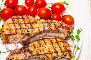Steak with tomatoes greens garlic on a white plate on the table. Photo of food, meat.
