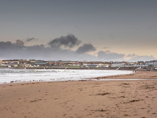 View on Kilkee beach and town houses in the background. County Clare, Ireland. Nobody. Popular summer resort. Atlantic ocean, Irish seascape. Cloudy sky.