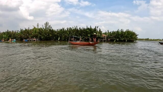 Fisherman casting net from a small boat  on Thu Bon river, Vietnam