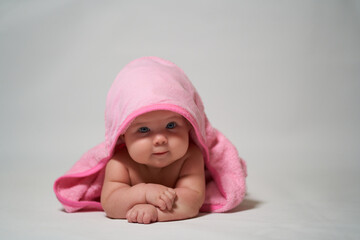 Portrait of a baby on a light background with a pink towel