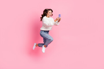 Full length photo of excited funky lady wear white sweater jumping typing apple samsung device isolated pink color background