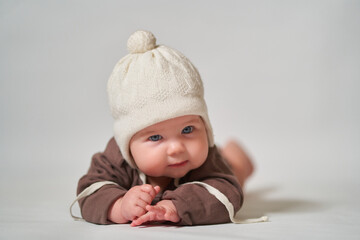 portrait of an infant on a light background in a warm knitted white hat