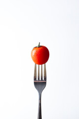 close-up on a cherry tomato stabbed on a fork on a white background