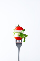 close-up of a pomelo cherry feta cheese sprig of parsley stabbed on a fork on a white background
