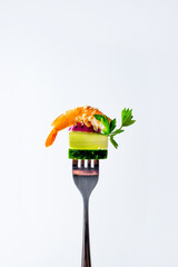 close-up of a shrimp piece of cucumber leek and parsley on a fork on a white background