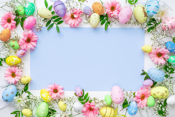 Colorful eggs with flowers on a white and blue background. Easter design in pastel colors with space for text. Holiday template, top view.
