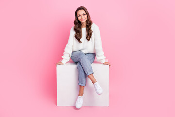 Full length photo of cute adorable lady wear white sweater sitting cube smiling isolated pink color background