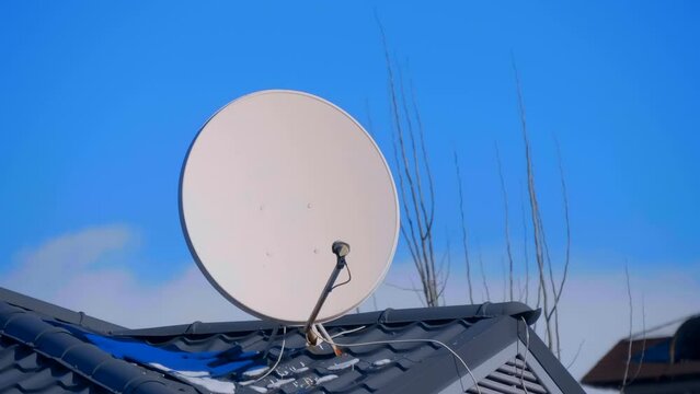 A satellite dish on the roof of a house in a remote village receives a TV and Internet signal. Shot in motion