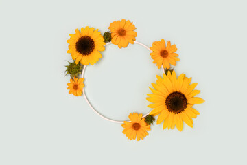 Wreath made of sunflowers and arnica flowers on a blue background. Creative concept.