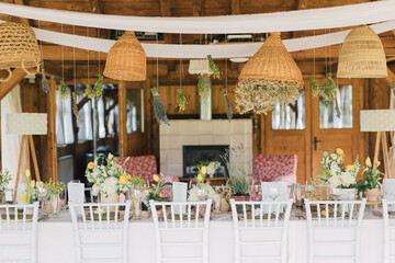 Beautiful rustic style design for a garden event table setting. Rustic arrangements with greenery and aromatic flowers for a bohemian intimate wedding. Country home celebration decor.