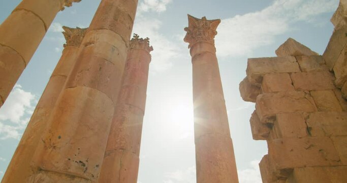 Bottom perspective of pillars shown in sunshine Temple of Artemis in Jerash, Jordan. Ionic columns of ruins of ancient building during summer. Middle East travel and architecture. 4k panning shot