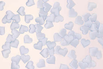 Texture made of blue textile confetti in a heart shape on a silver glittering background.