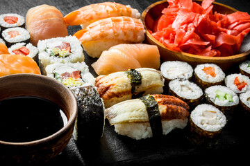 Various rolls, sushi and maki on a stone Board with soy sauce and ginger.
