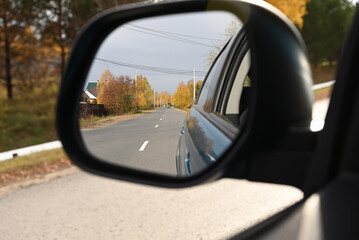 view through the side mirror of the autumn forest