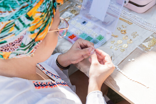 Latin Woman making handmade stone jewelry, home workshop. Craftswoman creating jewelry. Art, hobby, craft concept