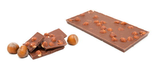 Whole bar and pieces of milk chocolate with hazelnuts isolated on white background. Copy space.