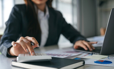 businesswoman using calculator working at office with document on her desk, doing planning analyzing the financial report, business plan investment,