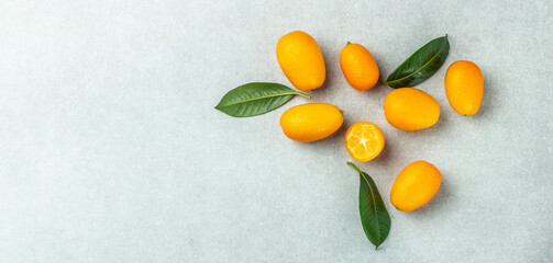 Raw orange kumquats on a light background, organic food market. Long banner format. top view