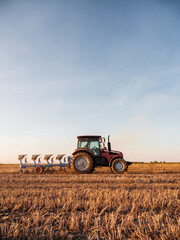Obraz premium Tractor plowing and preparing stubble field for cultivating and seeding crops