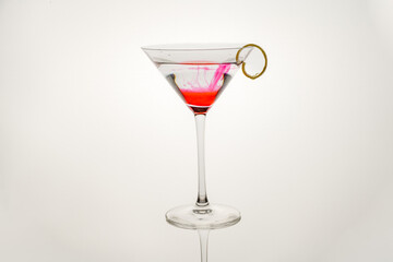 pink lemonade gin cocktail with a lemon twist isolated on a white background