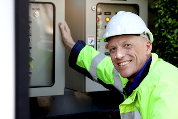Portrait of happy smiling senior elderly mature electrical engineer wearing safety vest and helmet...