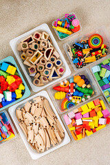Toy Storage boxs in the children's room. Plastic containers with colorful wooden toys. Organizing and Storage Ideas in nursery. Clean up toys and reduce the clutter. Top view