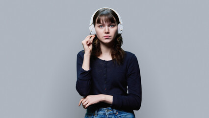 Serious young female in headphones looking at camera showing mouth shut gesture