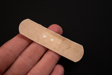 Hand holding adhesive plaster with copy space. Top view, close up.