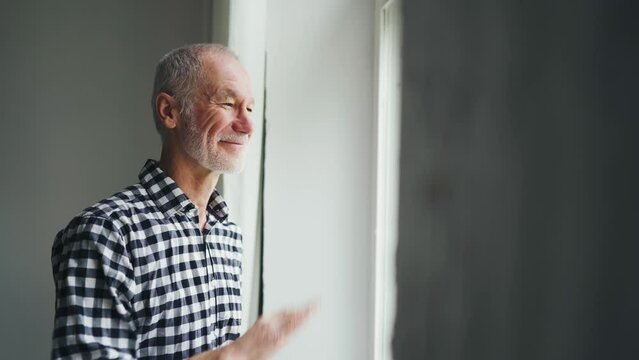 The old man at the window says goodbye, waving his hand. Waving goodbye.