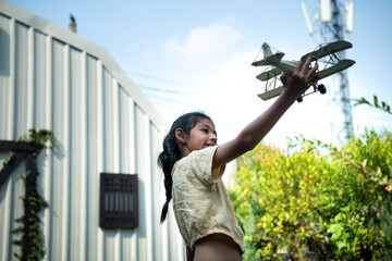 Portrait of a little girl in the front yard. with model aircraft which is the dream of a child who wants to be a pilot.