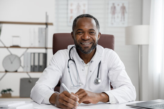 African American Male Doctor Welcomes Online Patient Consultation In Laptop. An Office Providing Telemedicine Services. Online Medicine And Telemedicine Concept.