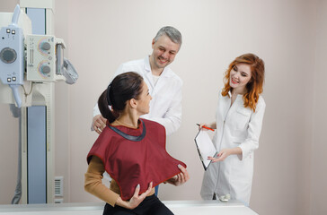 Obraz premium A male radiologist, together with an assistant, prepares the patient for an X-ray.