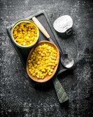 Open tin can with canned corn on the cutting Board.